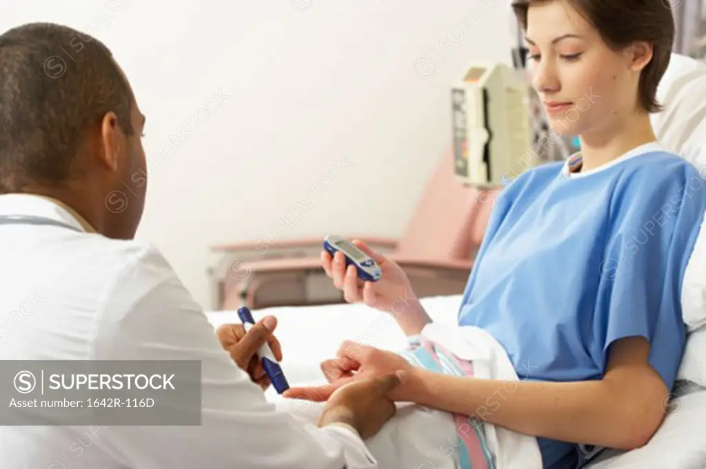Rear view of a male doctor taking a blood sample from a female patient's finger