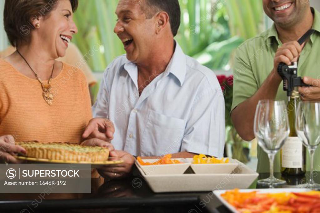 Stock Photo: 1646R-192 Close-up of a mature couple looking at each other with a mature man unscrewing the cork of a wine bottle