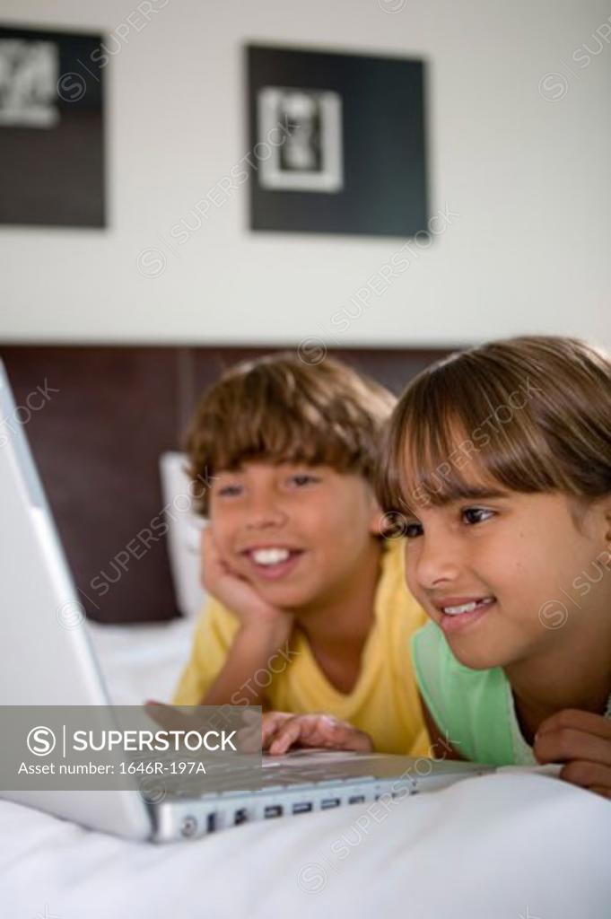 Stock Photo: 1646R-197A Close-up of a girl lying in the bed with her brother using a laptop