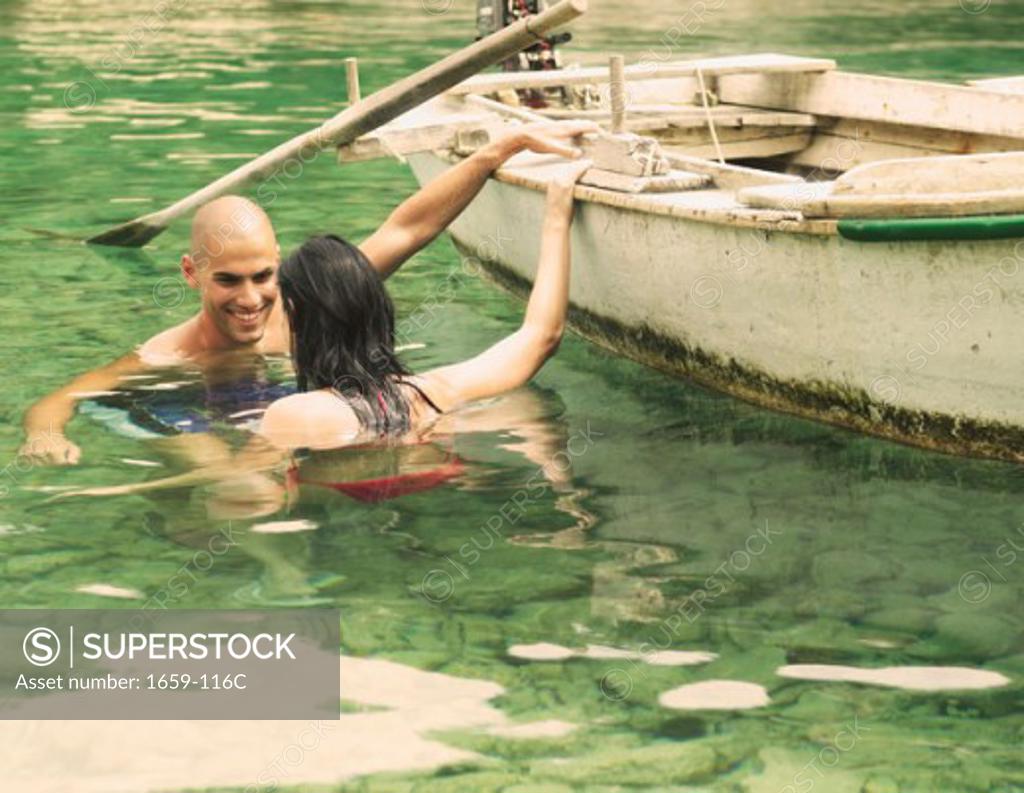 Stock Photo: 1659-116C Young couple swimming near a boat