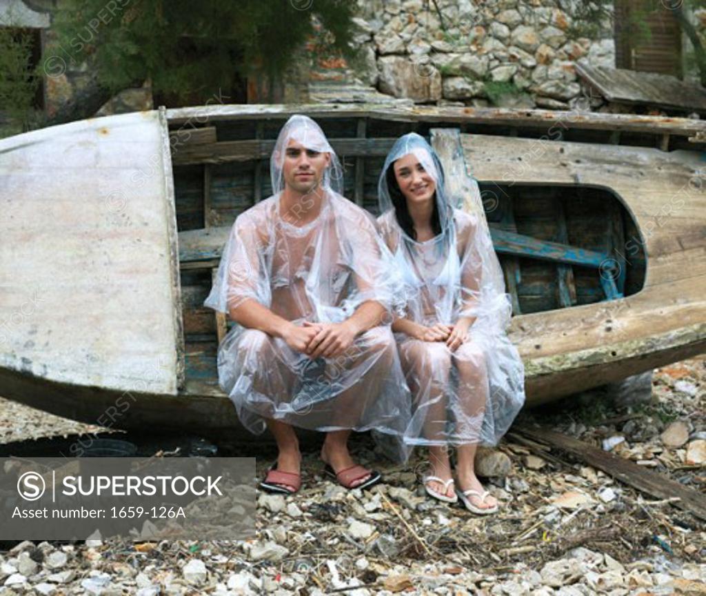 Stock Photo: 1659-126A Young couple wearing raincoats and sitting on a boat