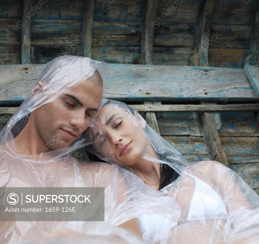 Stock Photo: 1659-126E Young couple wearing raincoats and sleeping in a boat
