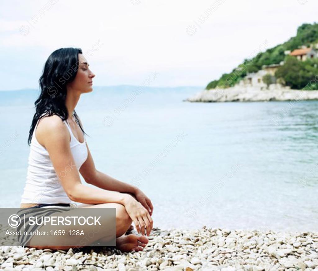 Stock Photo: 1659-128A Side profile of a young woman meditating on the beach