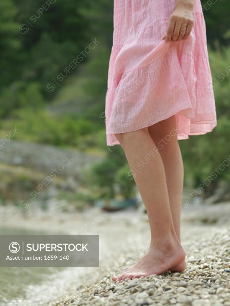 Stock Photo: 1659-140 Low section view of a young woman standing on the beach