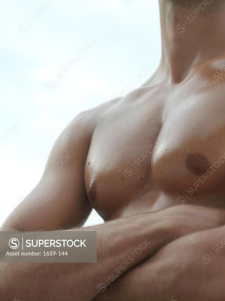 Stock Photo: 1659-144 Mid section view of a bare chested young man with his arms crossed
