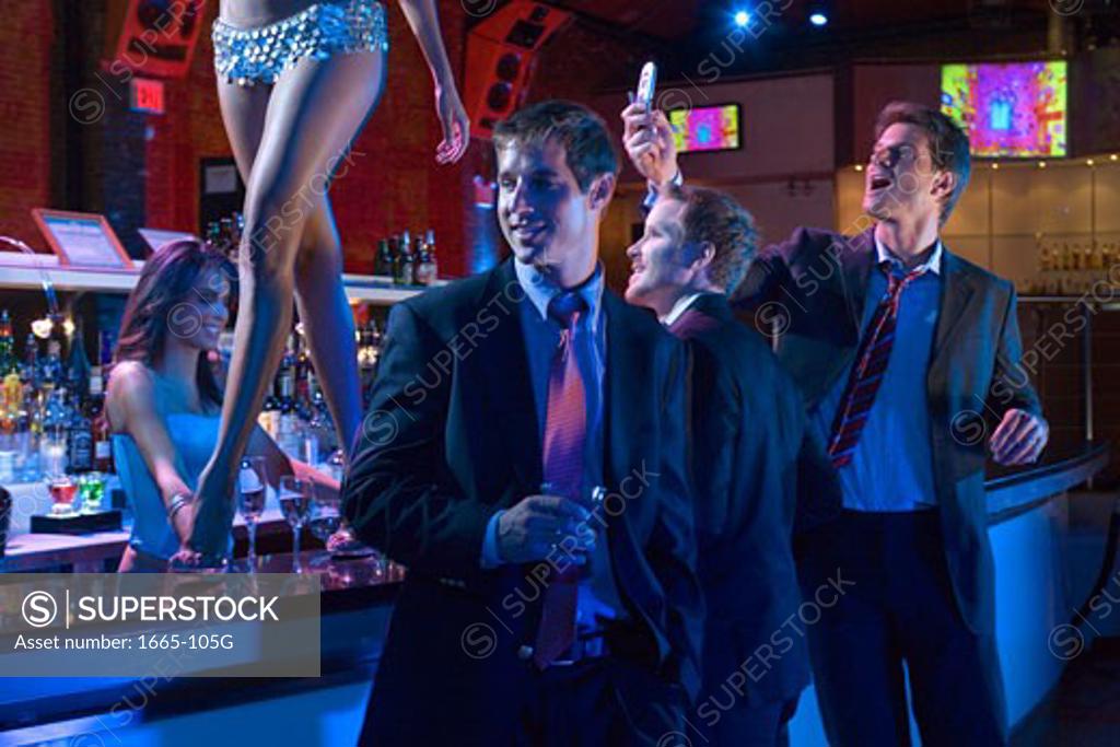Stock Photo: 1665-105G Three young men flirting with a dancer in a nightclub