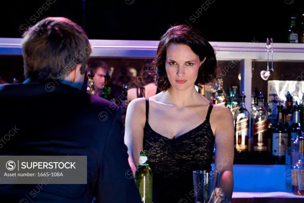 Stock Photo: 1665-108A Portrait of a female bartender holding a glass with a young man standing in front of her