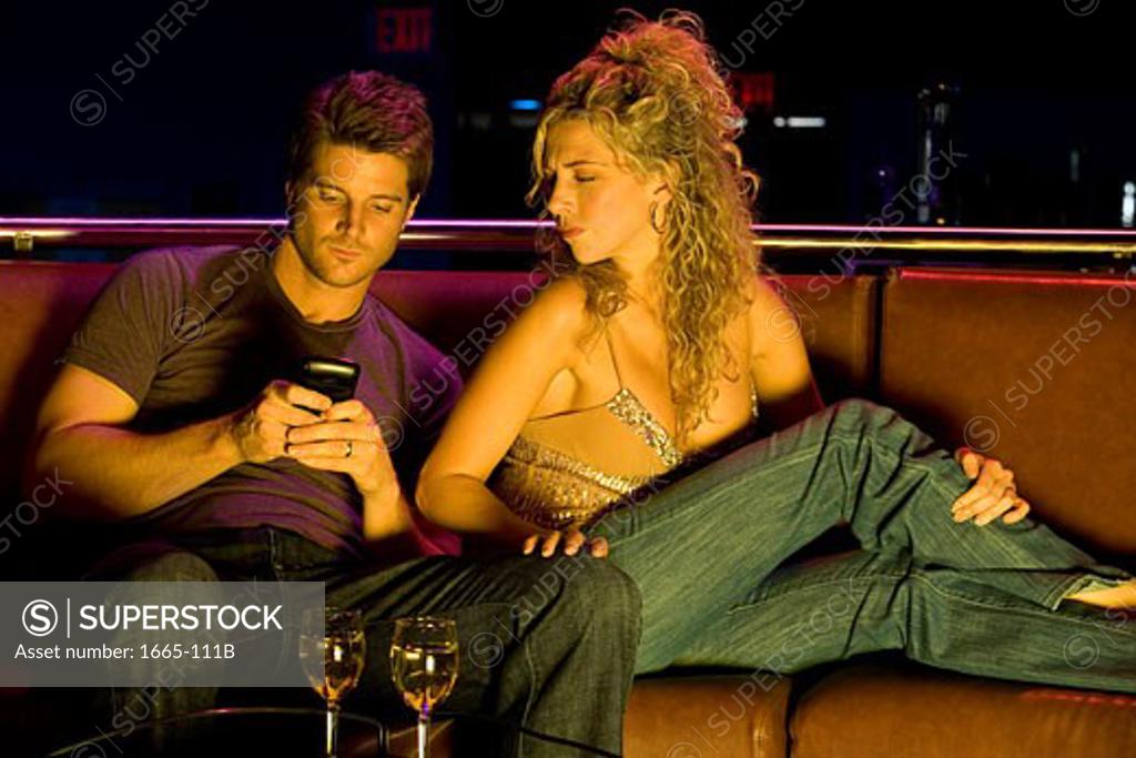 Stock Photo: 1665-111B Close-up of a young man using a mobile phone with a young woman sitting beside him