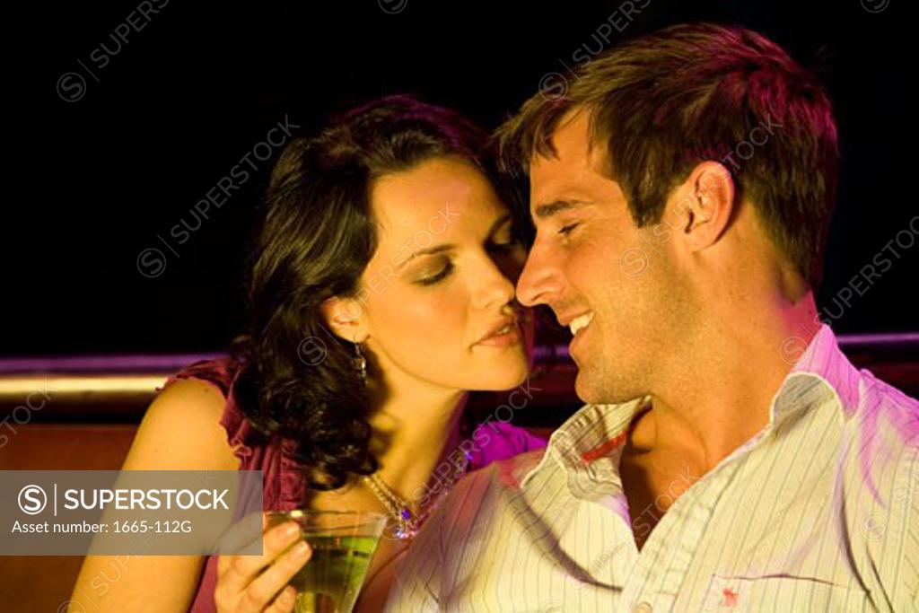 Stock Photo: 1665-112G Close-up of a young woman sitting with a young man in a nightclub and holding a cocktail