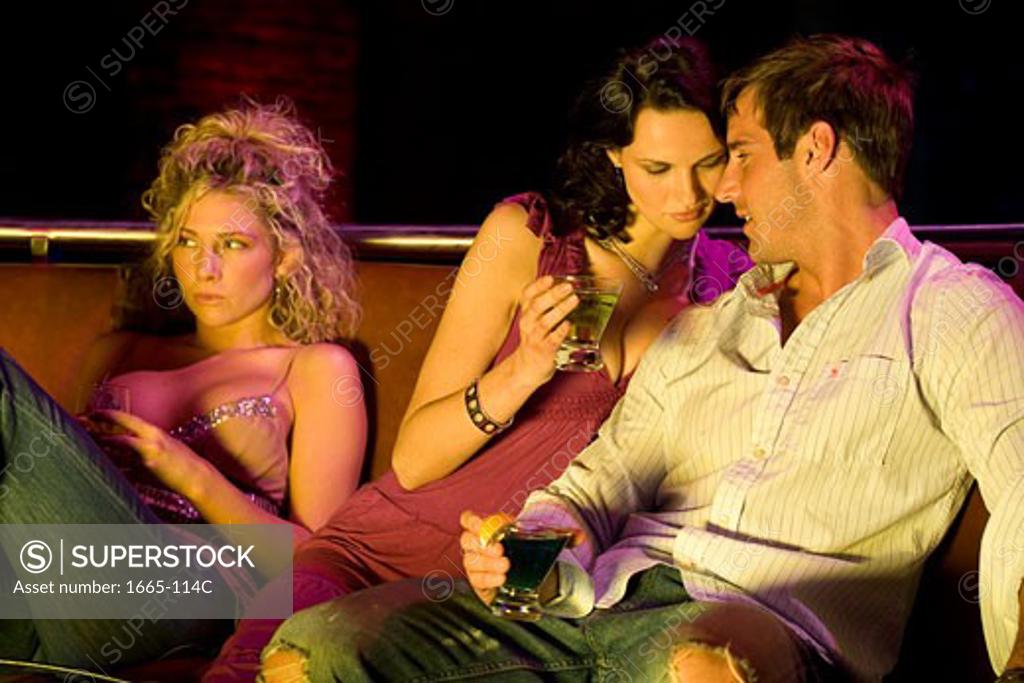 Stock Photo: 1665-114C Close-up of a young couple holding cocktails and a young woman sitting beside them