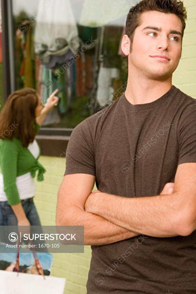Stock Photo: 1670-105 Close-up of a teenage boy looking sideways with a young woman shopping behind him