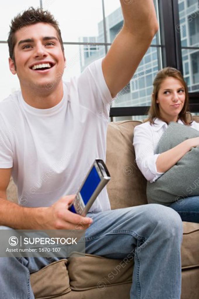 Stock Photo: 1670-107 Close-up of a teenage boy holding a remote control with a young woman sitting beside him