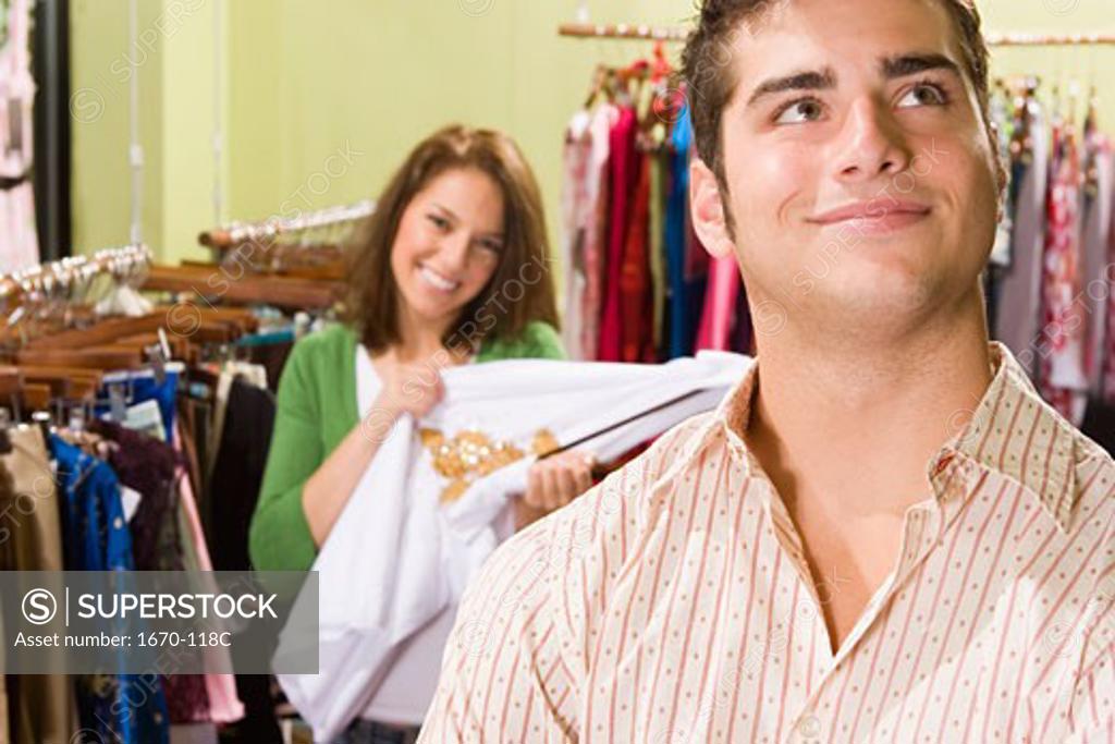 Stock Photo: 1670-118C Close-up of a teenage boy in a clothing store with a young woman standing behind him and smiling