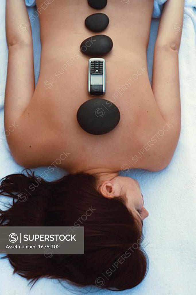 Stock Photo: 1676-102 High angle view of a young woman with stones and a mobile phone on her back