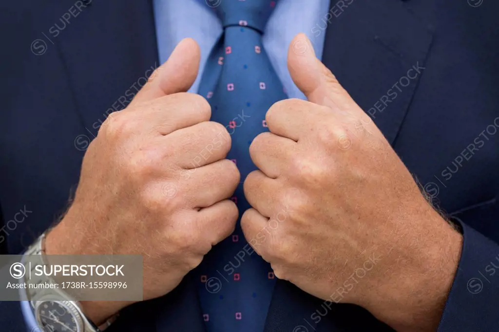 Close-up of man's hands in suit holding the rim of his jacket.