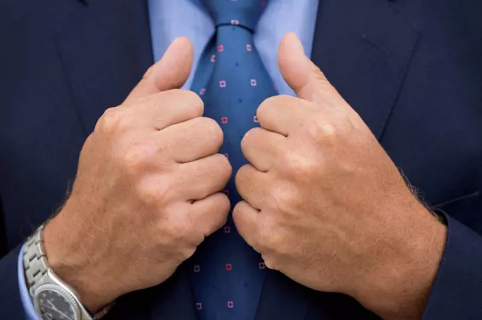 Close-up of man's hands in suit holding the rim of his jacket.