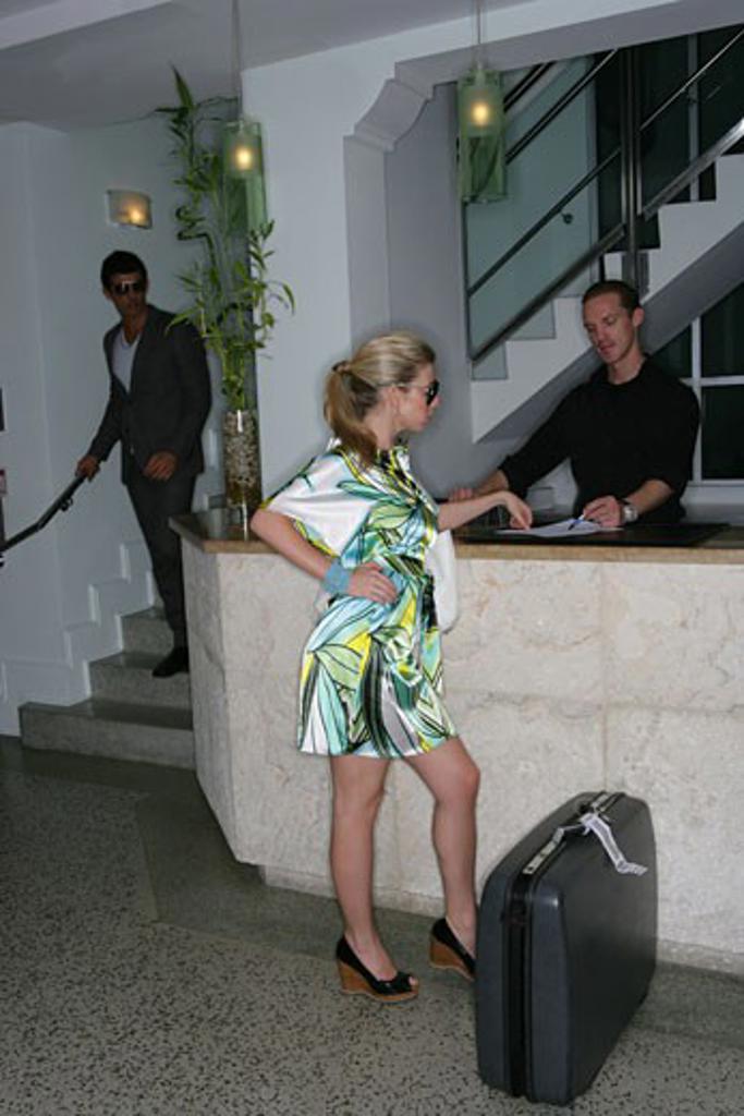 Fashionable woman in hotel lobby with suitcase.
