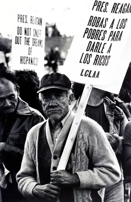 Reagan la roba a los pobres Migrant farm worker at a demonstration, Washington, D.C. Published 1981. Photograph shows an elderly man in the Solidarity Day march, holding a picket sign with the message: Pres. Reagan robas a los pobres para darle a los ricos, LCLAA, in a crowd at a protest. A sign in the background has the message: Pres. Reagan, do not snuff out the dreams of Hispanics!