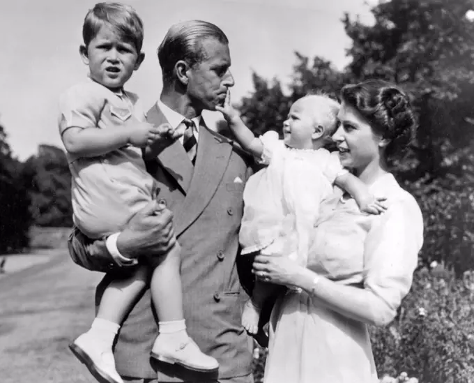 Photograph of Queen Elizabeth II (1926-) and the Duke of Edinburgh, Prince Phillip (1921-) holding Prince Charles (1948-) and Princess Anne (1950). Dated 1952
