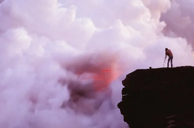 Hawaii, Big Island, Photographer on lava table filming lava flow into ocean