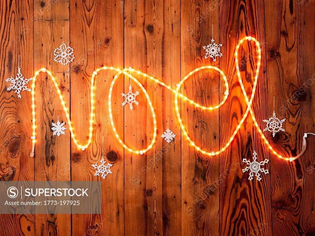Christmas lights spelling Noel against wood panelling