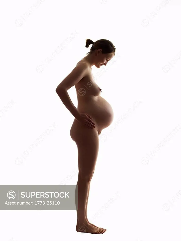 Silhouette of nude pregnant woman looking down at her stomach. Profile  view. - SuperStock