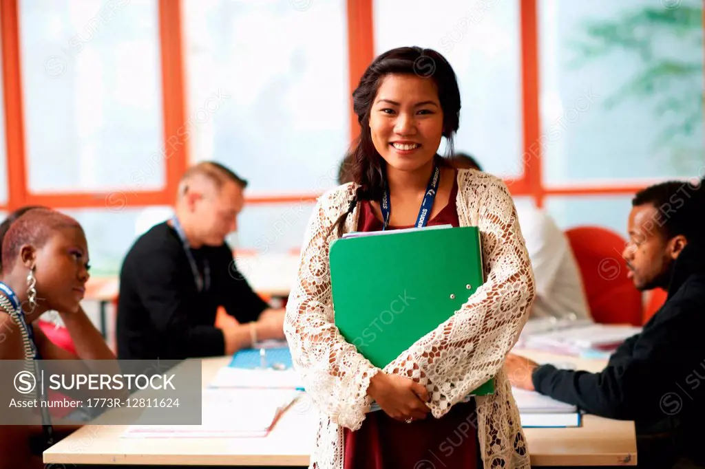 Portrait of female student holding file in front of class