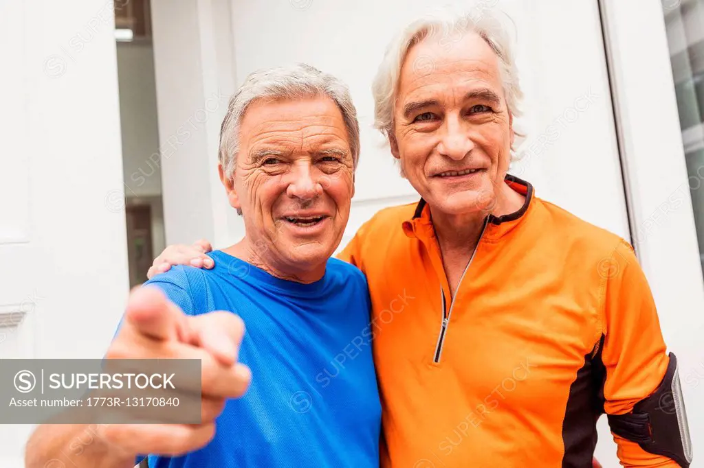 Portrait of two happy senior male runners at front door