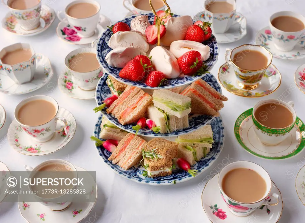 Vintage tea cups and sandwiches on cakestand prepared for afternoon tea
