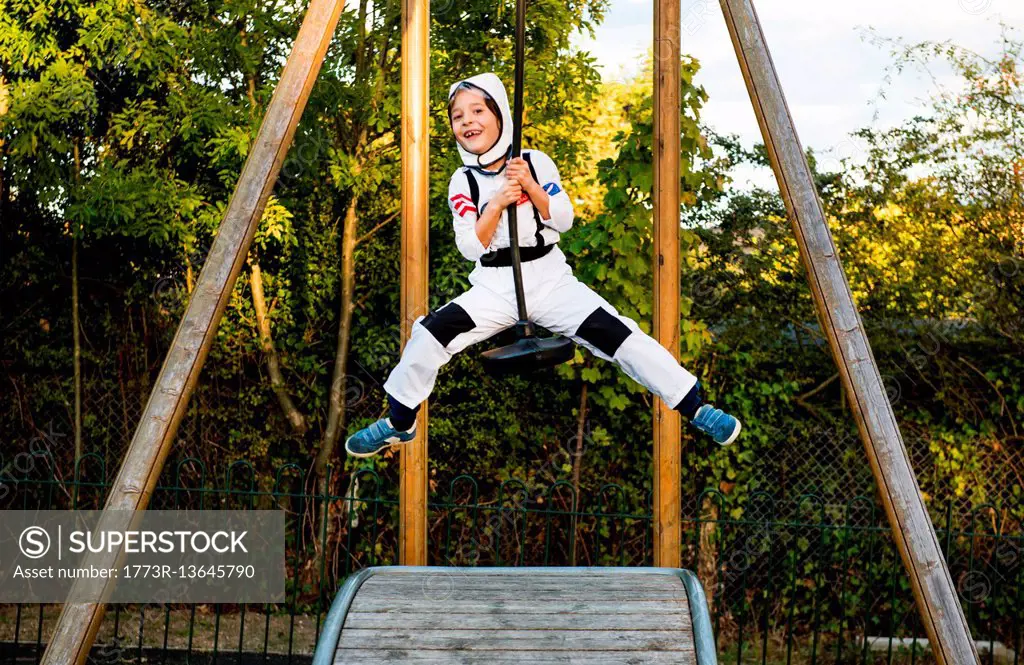 Portrait of boy in astronaut costume riding on playground zip wire