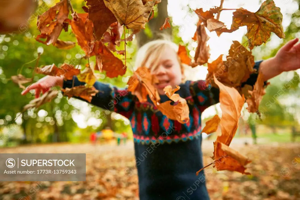 Girl throwing in autumn leaves