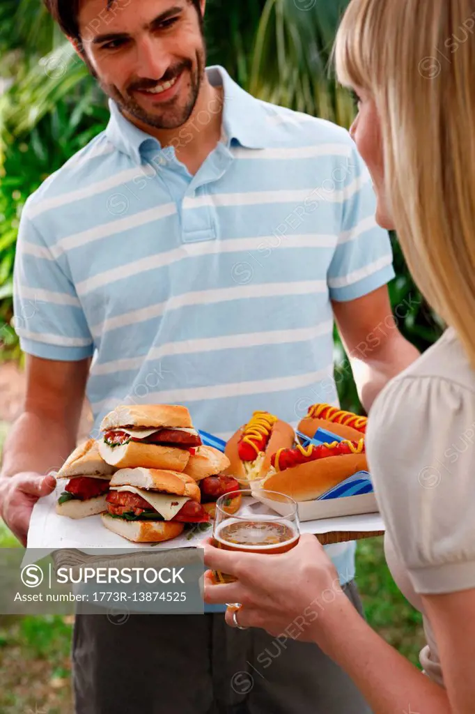 Man holding tray of burgers and hot dogs