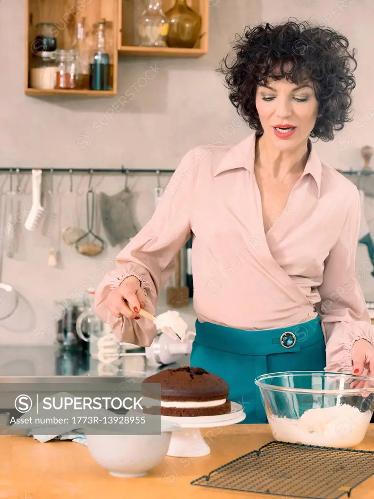 Woman decorating chocolate cake with dairy cream