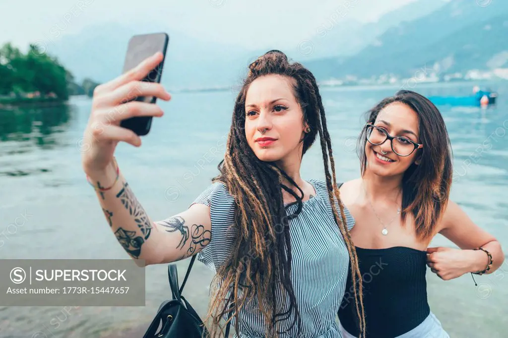 Girlfriends taking selfie by sea