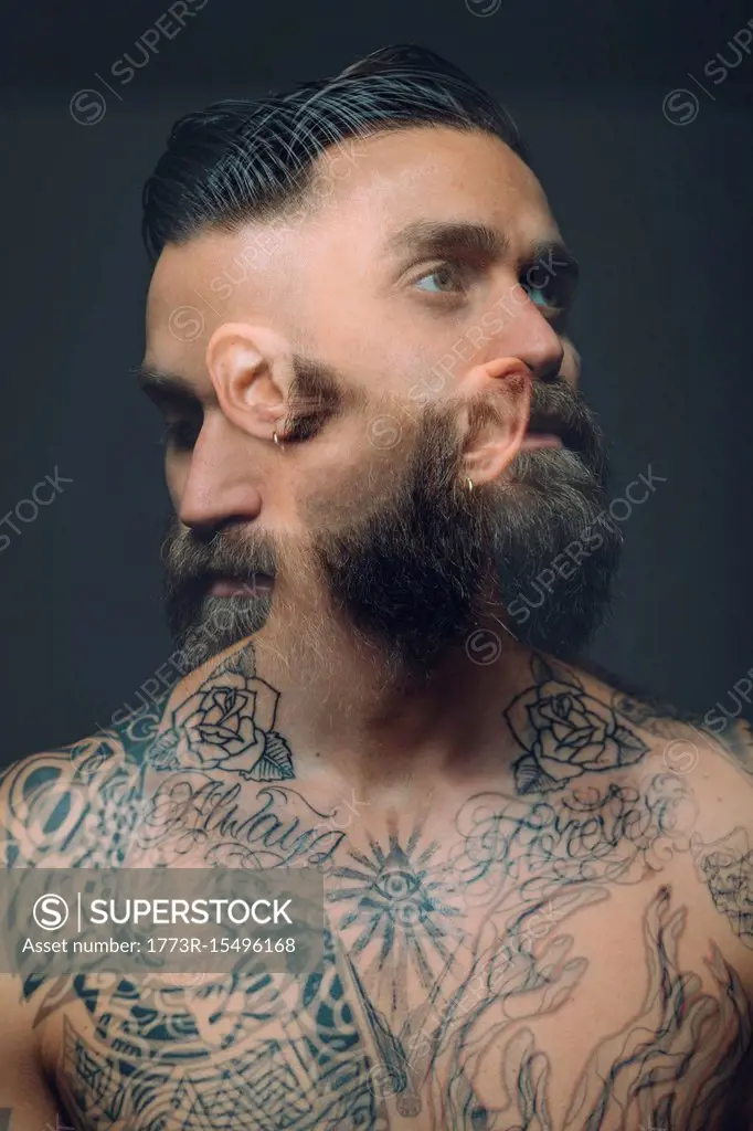 Multiple exposure of bare chested young man, covered in tattoos, worried,  pensive expression - SuperStock