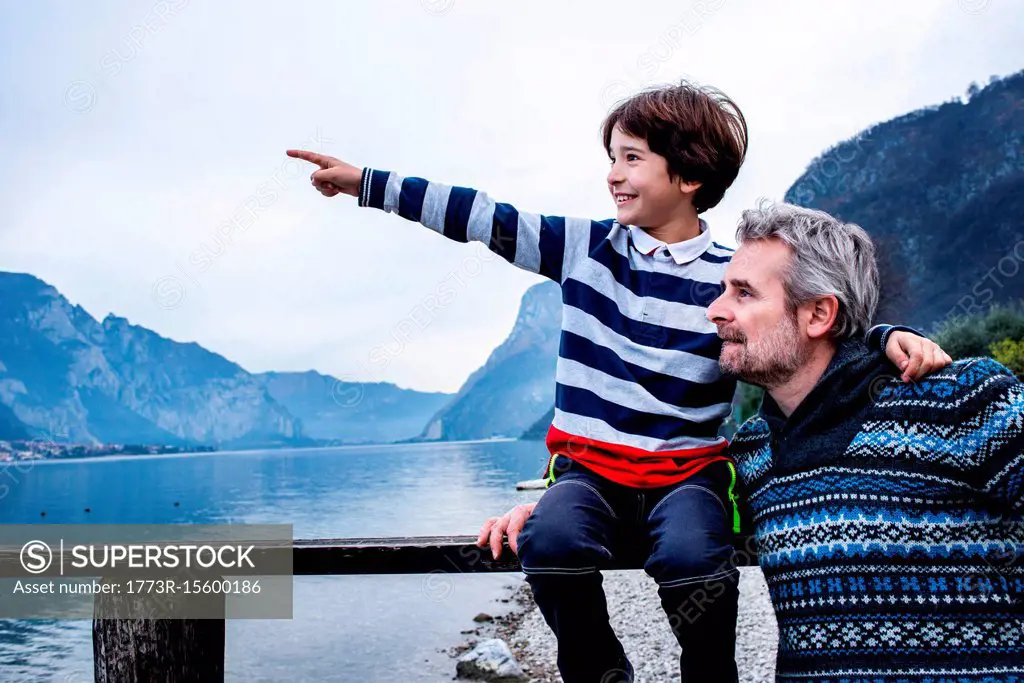 Boy and father pointing from lakeside pier, Lake Como, Onno, Lombardy, Italy
