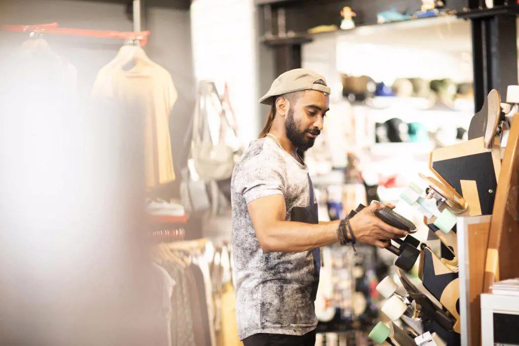 Man choosing skateboard in shop