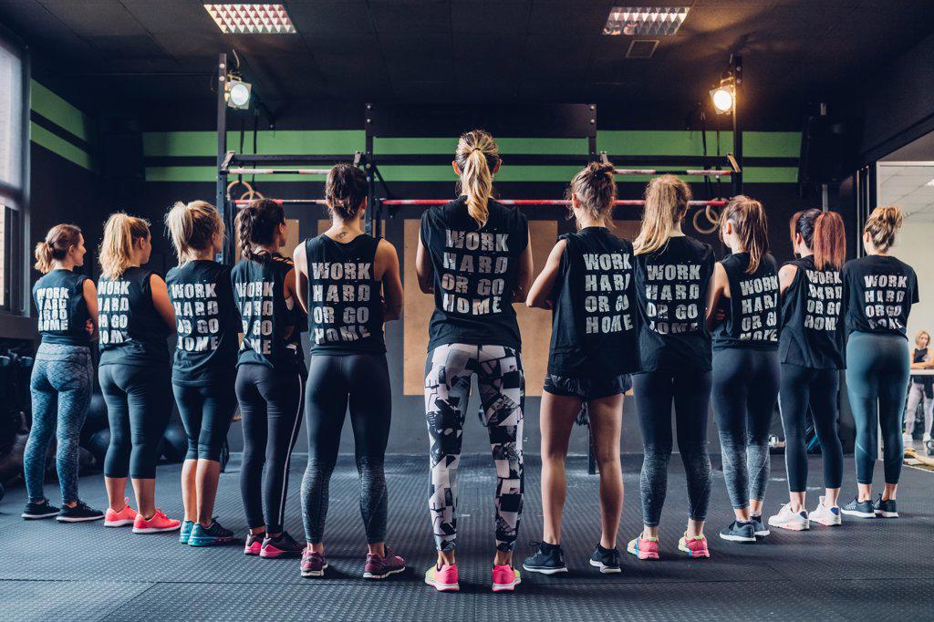 Group of women training in gym, wearing slogan t-shirts, rear view
