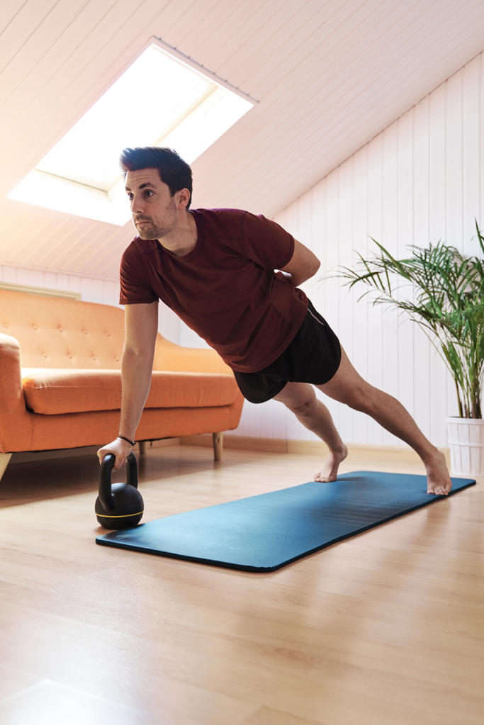 Man exercising at home, using kettlebell