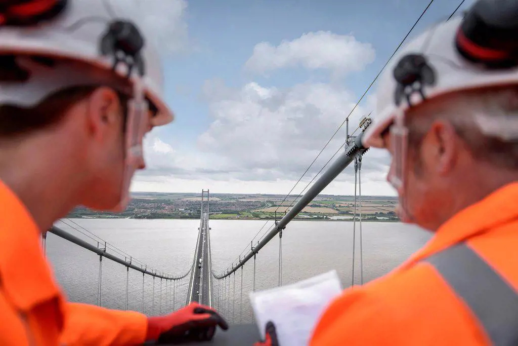 Bridge workers on top of suspension bridge. The Humber Bridge, UK was built in 1981 and at the time was the world's largest single-span suspension bri...
