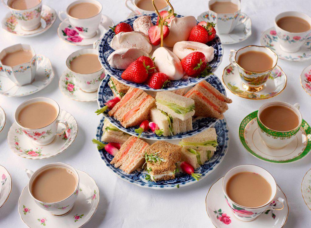 Vintage tea cups and sandwiches on cakestand prepared for afternoon tea