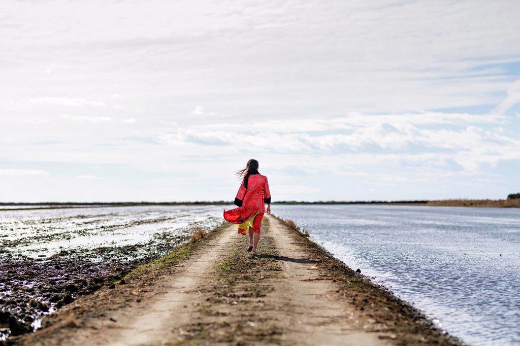 Rear view of young asian woman on dirt track by sea in traditional clothing, Tarragona, Catalonia, Spain