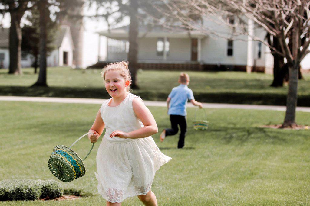 Girl and boy outdoors, holding Easter baskets, on Easter egg hunt