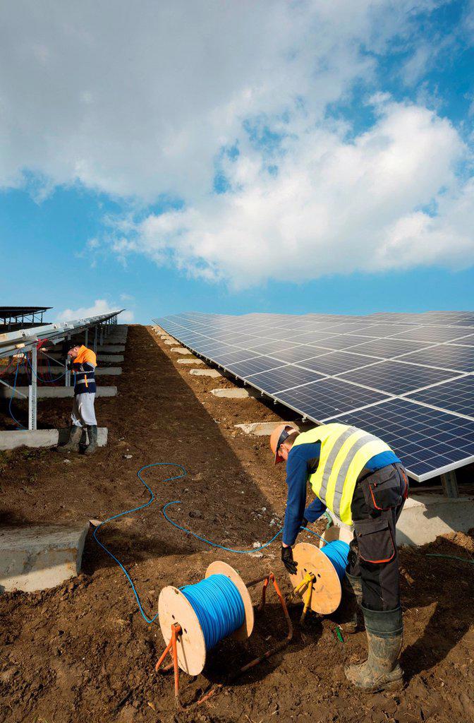 Engineers connecting solar panels on new solar farm, situated on former waste dump