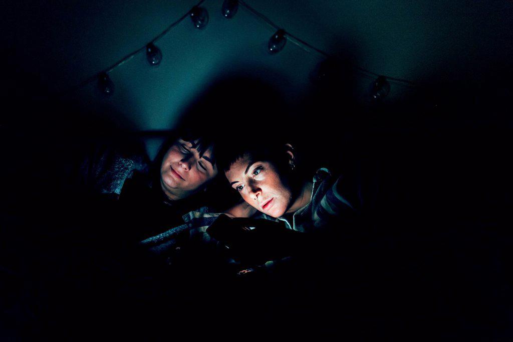 Women in bed in darkness using laptop