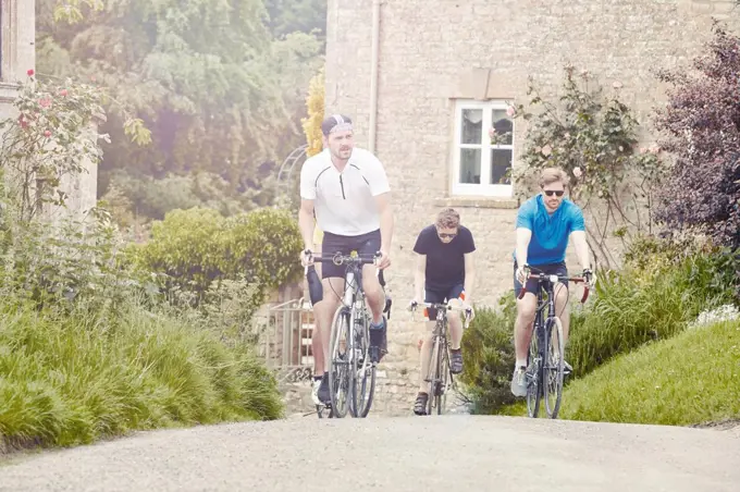 Cyclists riding through village, Cotswolds, UK