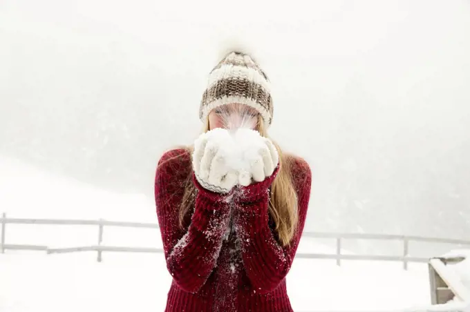 Young woman blowing handful of powder snow