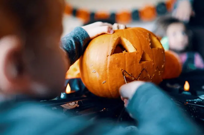 Rear view of a boy cutting a mouth in a pumpkin for a pumpkin head.