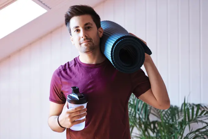 Man ready for exercise with mat and bottle
