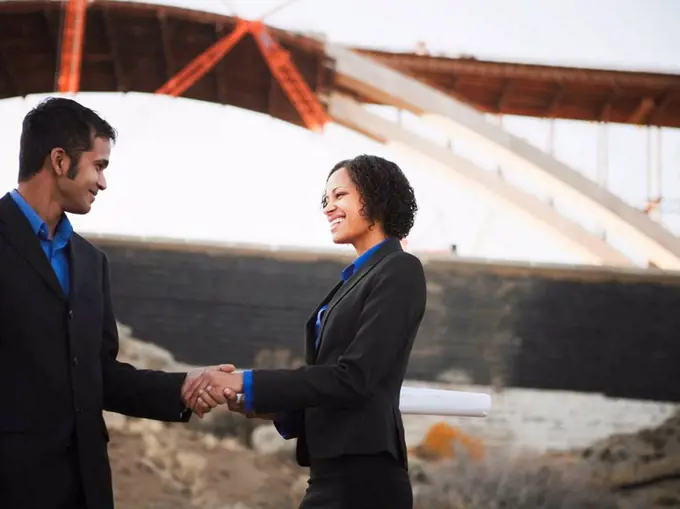 Man and woman on work site shaking hands